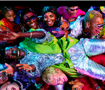 Ein MacBook Pro Display zeigt ein farbenfrohes Bild einer Person, die auf einer Party crowdsurft, und demonstriert das brillante Liquid Retina XDR Display